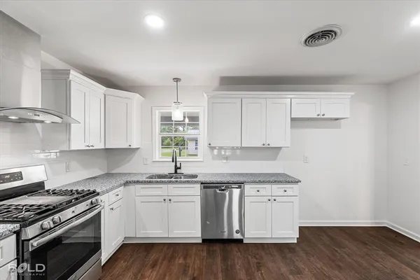 a kitchen with granite countertop white cabinets and white stainless steel appliances