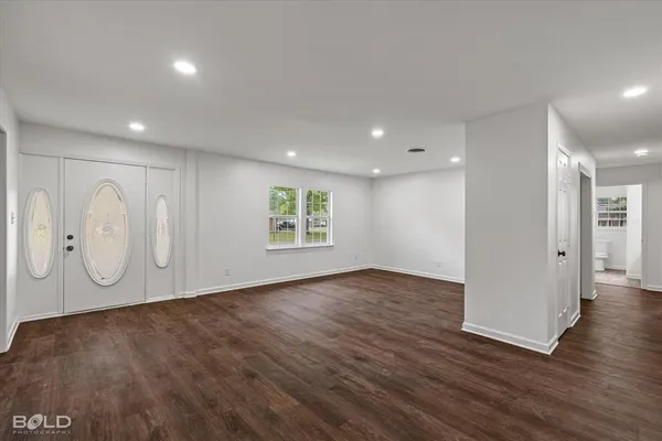 an empty room with wooden floor and window