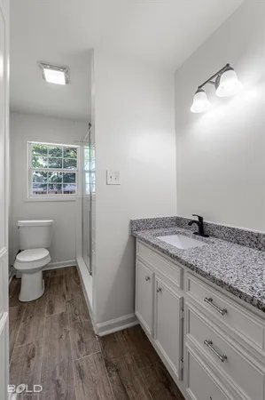 a bathroom with a granite countertop toilet a sink and a mirror