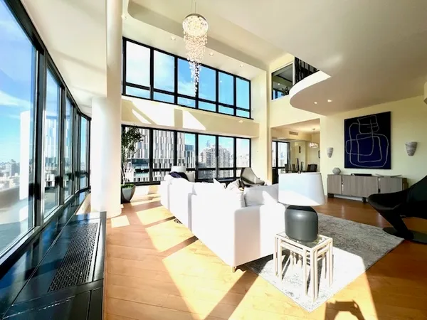 a living room with furniture a rug kitchen view and a large window