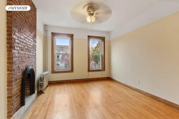 a view of an empty room with a window and wooden floor