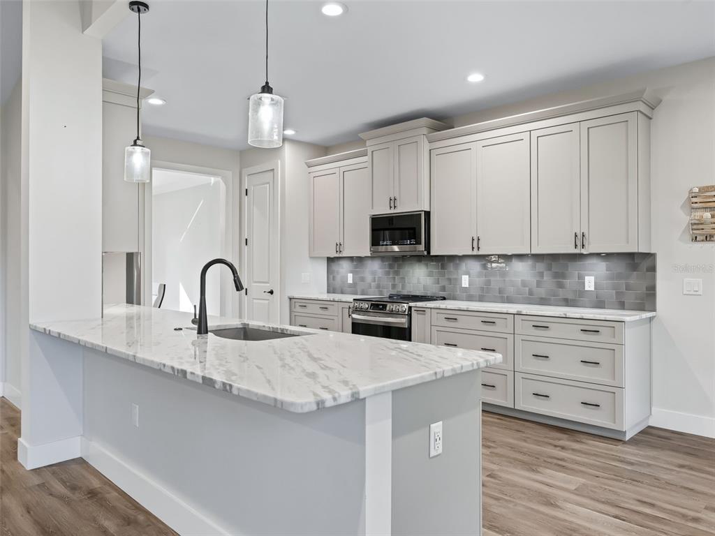 562 Dowling Circle Lady Lake, FL 32159 - Photo 13 of 62 a kitchen with stainless steel appliances granite countertop a sink a stove and a wooden floors
