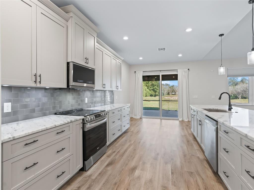 562 Dowling Circle Lady Lake, FL 32159 - Photo 18 of 62 a large kitchen with stainless steel appliances granite countertop a stove a sink and a microwave