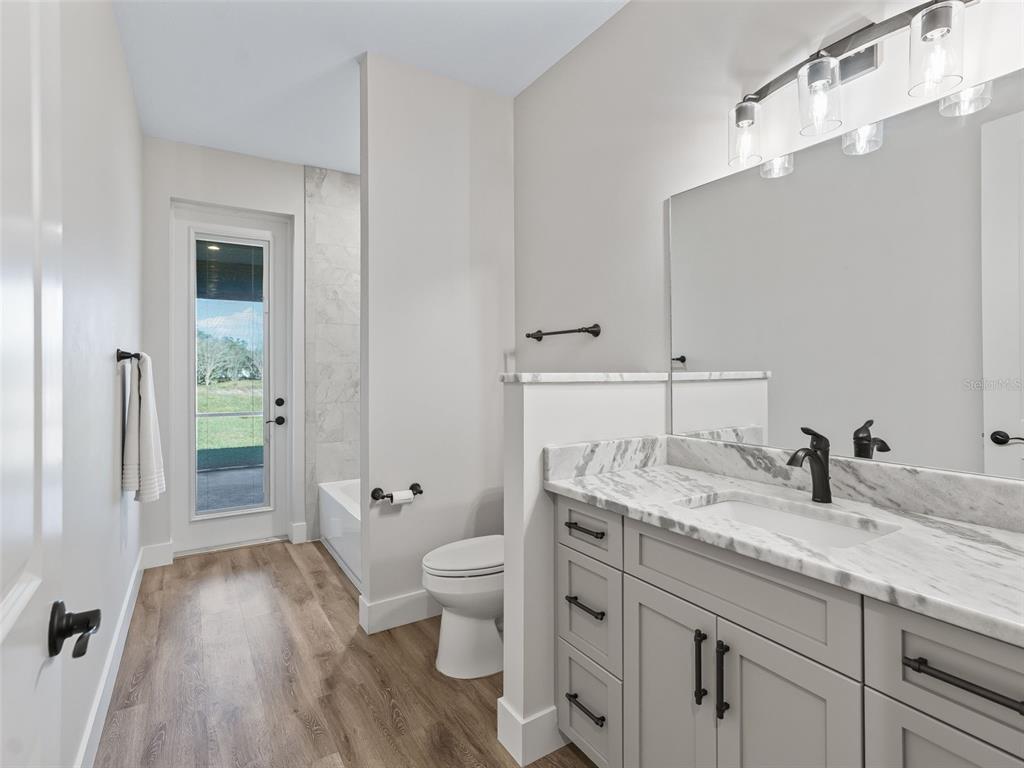 562 Dowling Circle Lady Lake, FL 32159 - Photo 37 of 62 a bathroom with a granite countertop sink a toilet and a large mirror