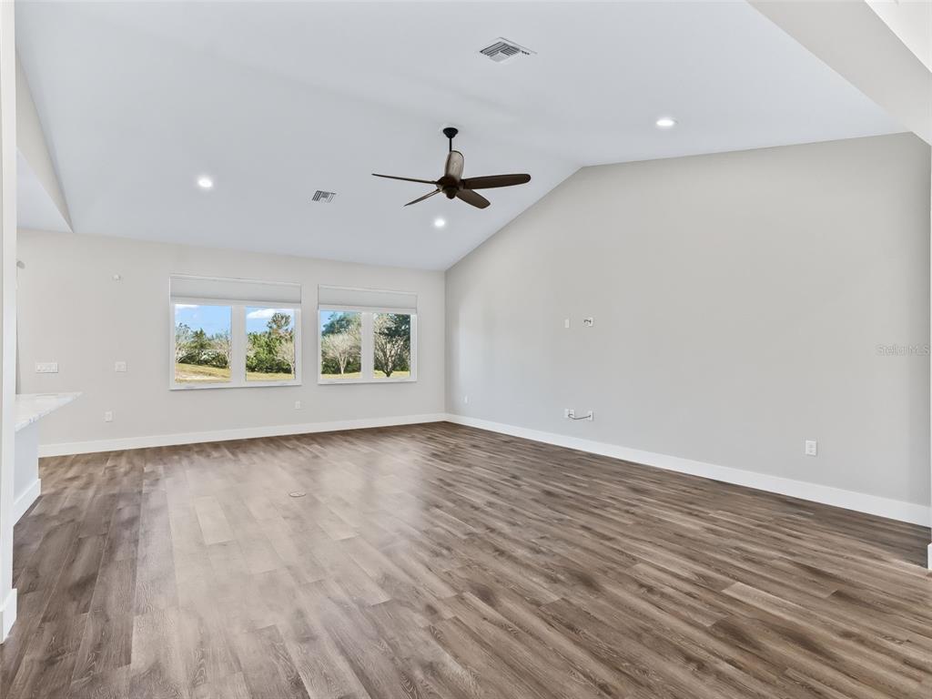 562 Dowling Circle Lady Lake, FL 32159 - Photo 7 of 62 an empty room with wooden floor ceiling fan and windows