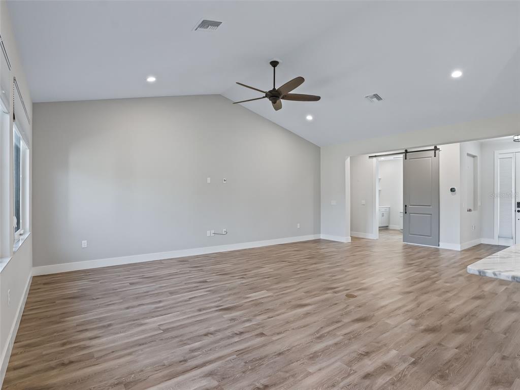 562 Dowling Circle Lady Lake, FL 32159 - Photo 10 of 62 a view of an empty room with wooden floor and a ceiling fan