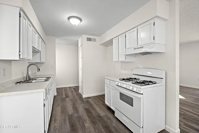 a kitchen with stainless steel appliances granite countertop white cabinets stove top oven and sink