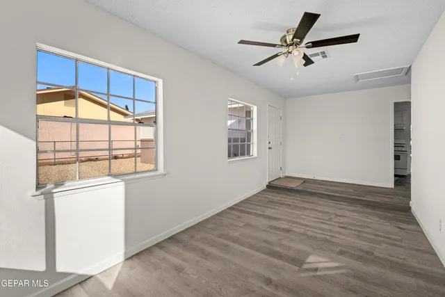 a view of empty room with wooden floor and fan