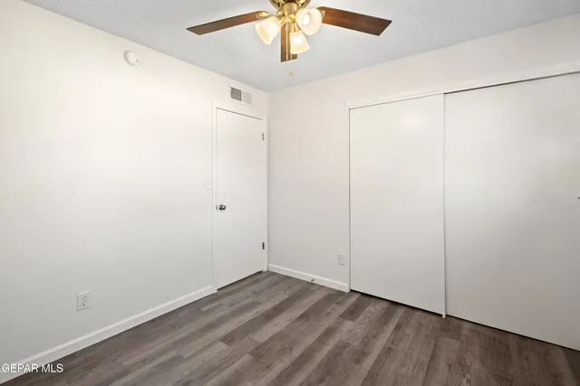 an empty room with a ceiling fan and wooden floor