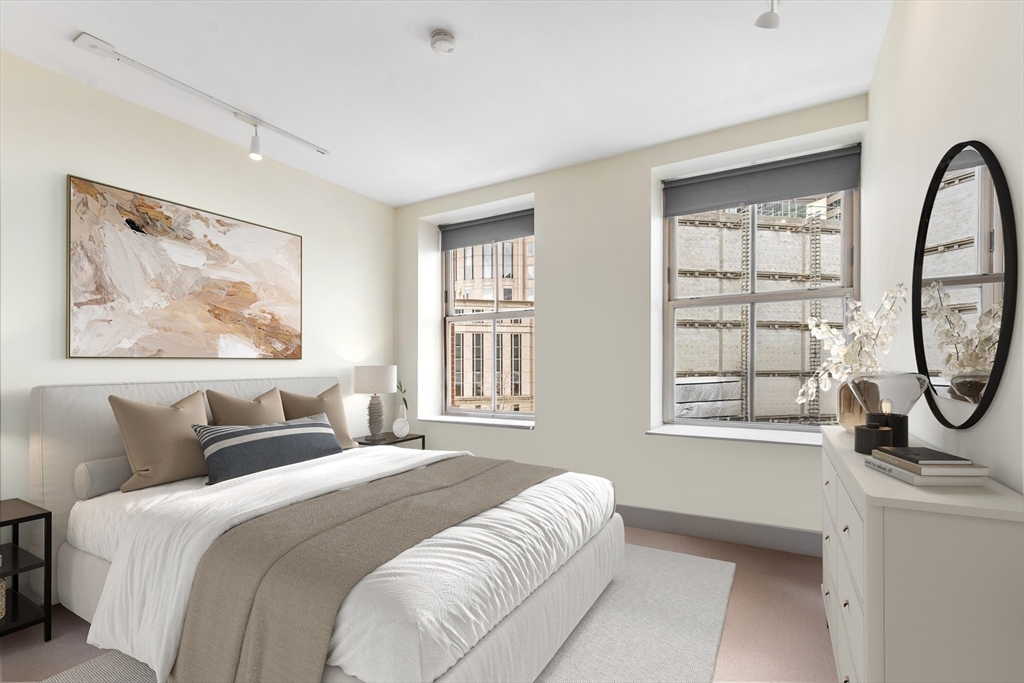181 Essex Street, Unit E402 Boston, MA 02111 - Photo 4 of 10 a bedroom with a bed a mirror and windows