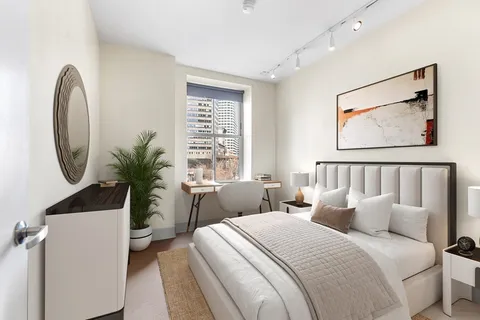 a bedroom with bed and a potted plant next to a window