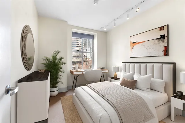 a bedroom with bed and a potted plant next to a window