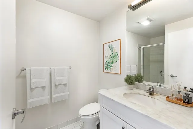 a bathroom with a granite countertop sink mirror vanity and toilet