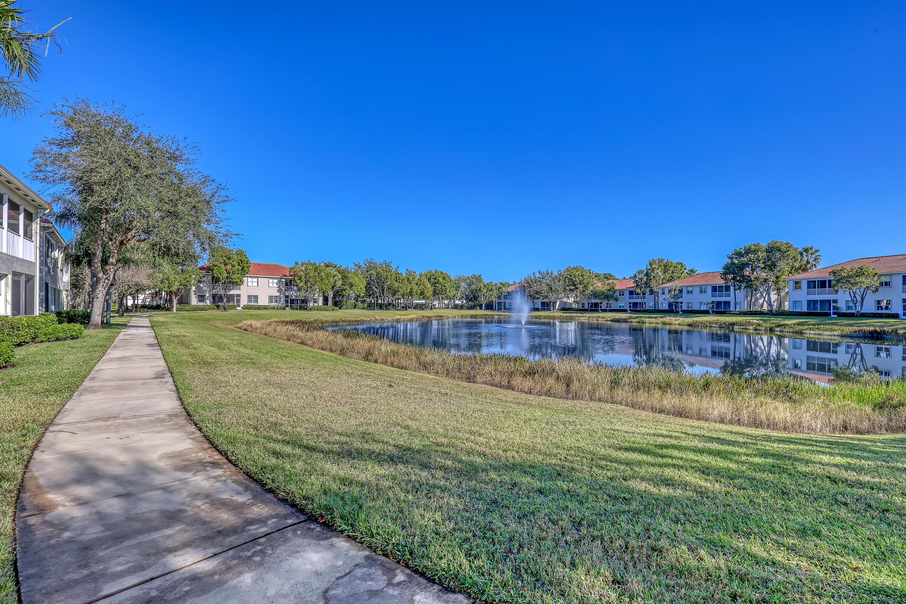 2136 Wingate Bend Wellington, FL 33414 - Photo 40 of 44 a view of a lake with a house in the background