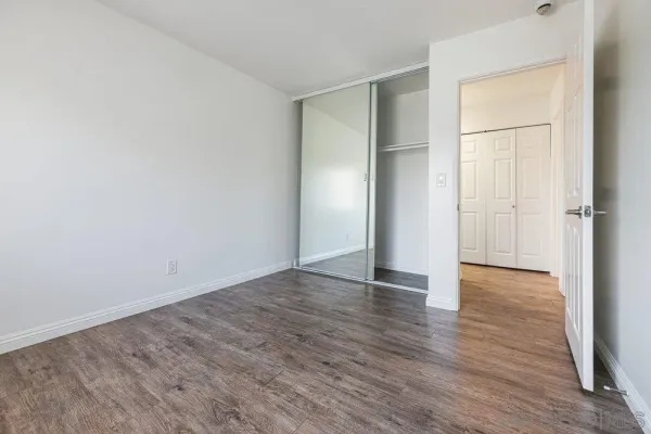 an empty room with wooden floor & closet area