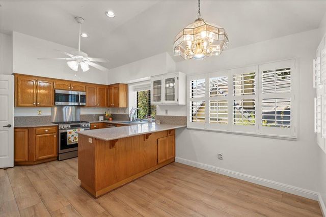 a kitchen with stainless steel appliances granite countertop a stove top oven a sink dishwasher a dining table and chairs with wooden floor