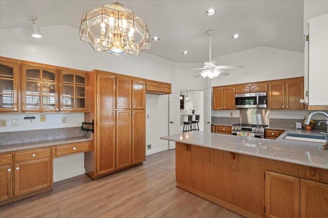 a large kitchen with stainless steel appliances a large counter top a sink dishwasher a kitchen island with wooden floor and cabinets