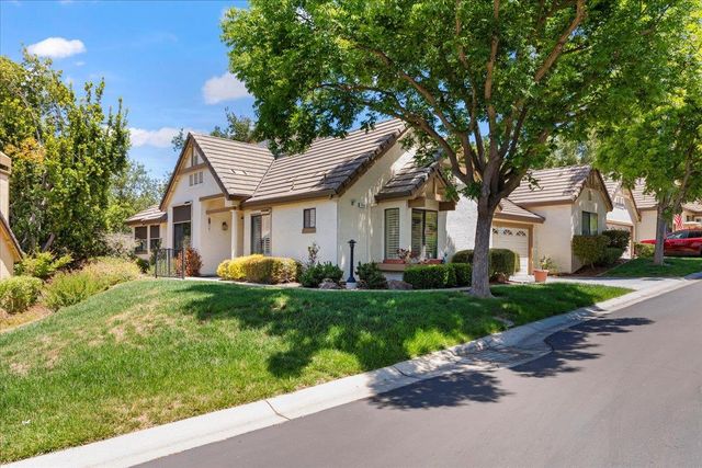 a front view of a house with a garden and trees