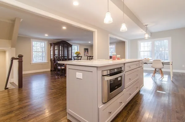 a kitchen with stainless steel appliances a stove top oven a sink dishwasher and a dining table with wooden floor