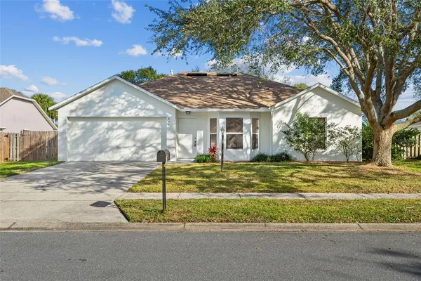 a view of a house with a big yard and large tree