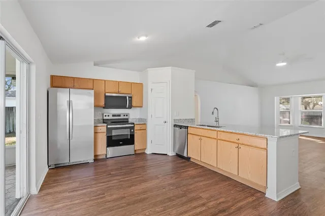 a kitchen with stainless steel appliances a stove top oven a sink and a refrigerator