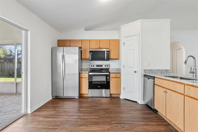 a kitchen with granite countertop a refrigerator and a stove top oven