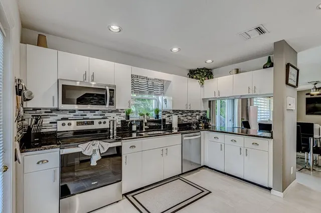 a kitchen with white cabinets and appliances