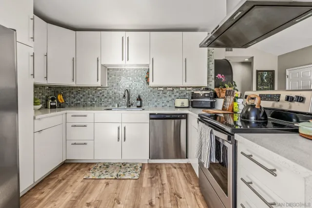 a kitchen with stainless steel appliances a stove a chimney a sink and a dining table