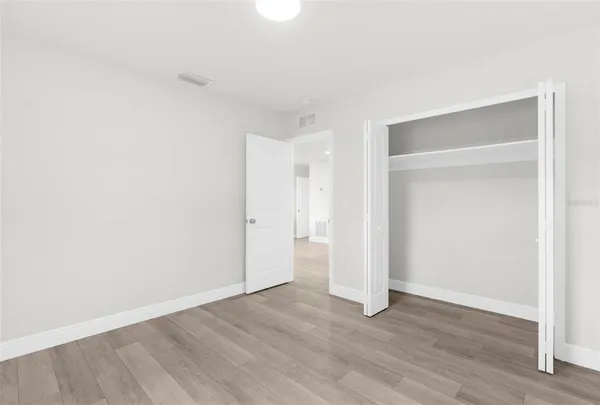 an empty room with wooden floor & closet