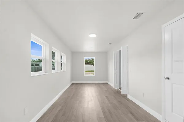 a view of a big room with wooden floor and windows