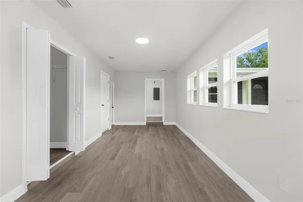 a view of an empty room with wooden floor and a window