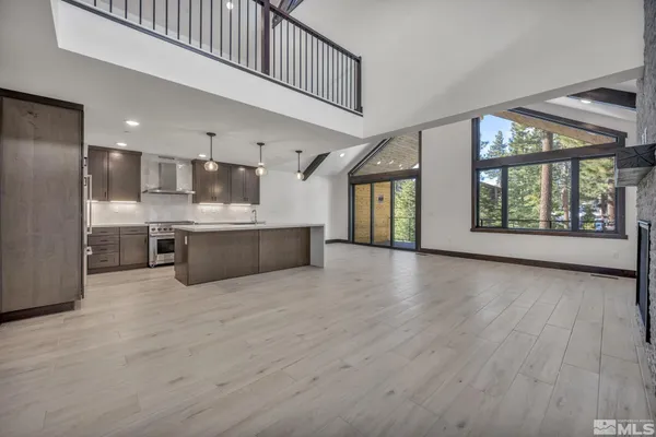 a view of a kitchen with kitchen island a sink wooden floor and a large window