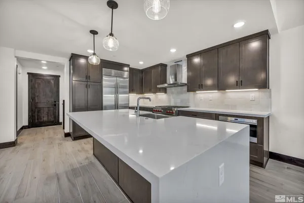 a large kitchen with kitchen island a large counter top a sink and stainless steel appliances