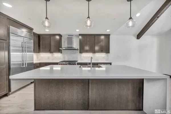 a large kitchen with a large counter top a sink stainless steel appliances and cabinets