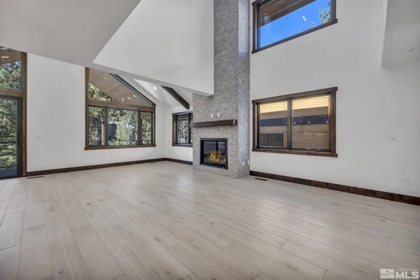 an empty room with wooden floor fireplace and windows