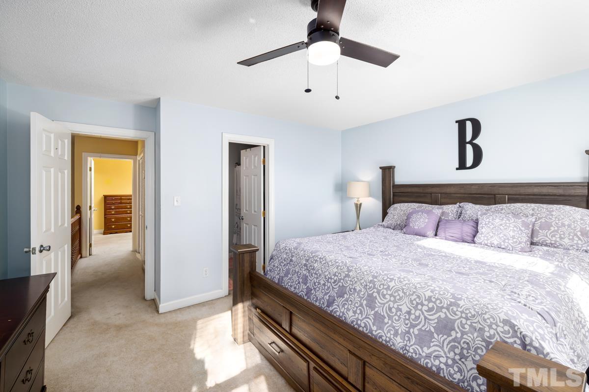 1202 Shadow Bark Court Raleigh, NC 27603 - Photo 24 of 27 a bedroom with a large bed and a chandelier