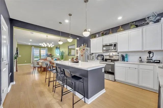 a kitchen with stainless steel appliances granite countertop a stove top oven a sink dishwasher a dining table and chairs with wooden floor