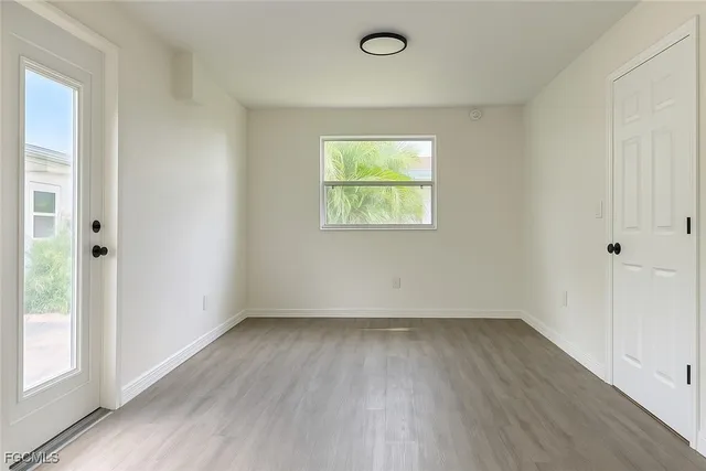 an empty room with wooden floor fan and windows