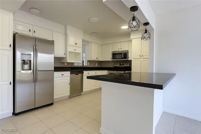 an empty room with windows and kitchen view