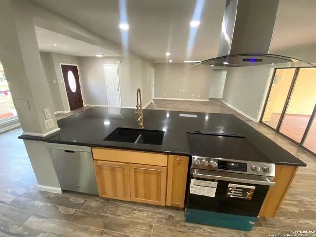 a kitchen with stainless steel appliances granite countertop a stove and a wooden floors