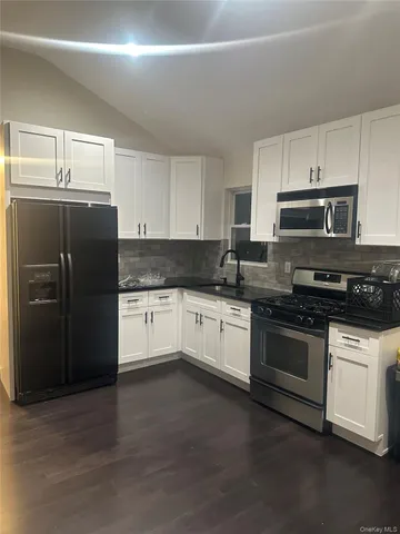 a kitchen with granite countertop white cabinets and stainless steel appliances
