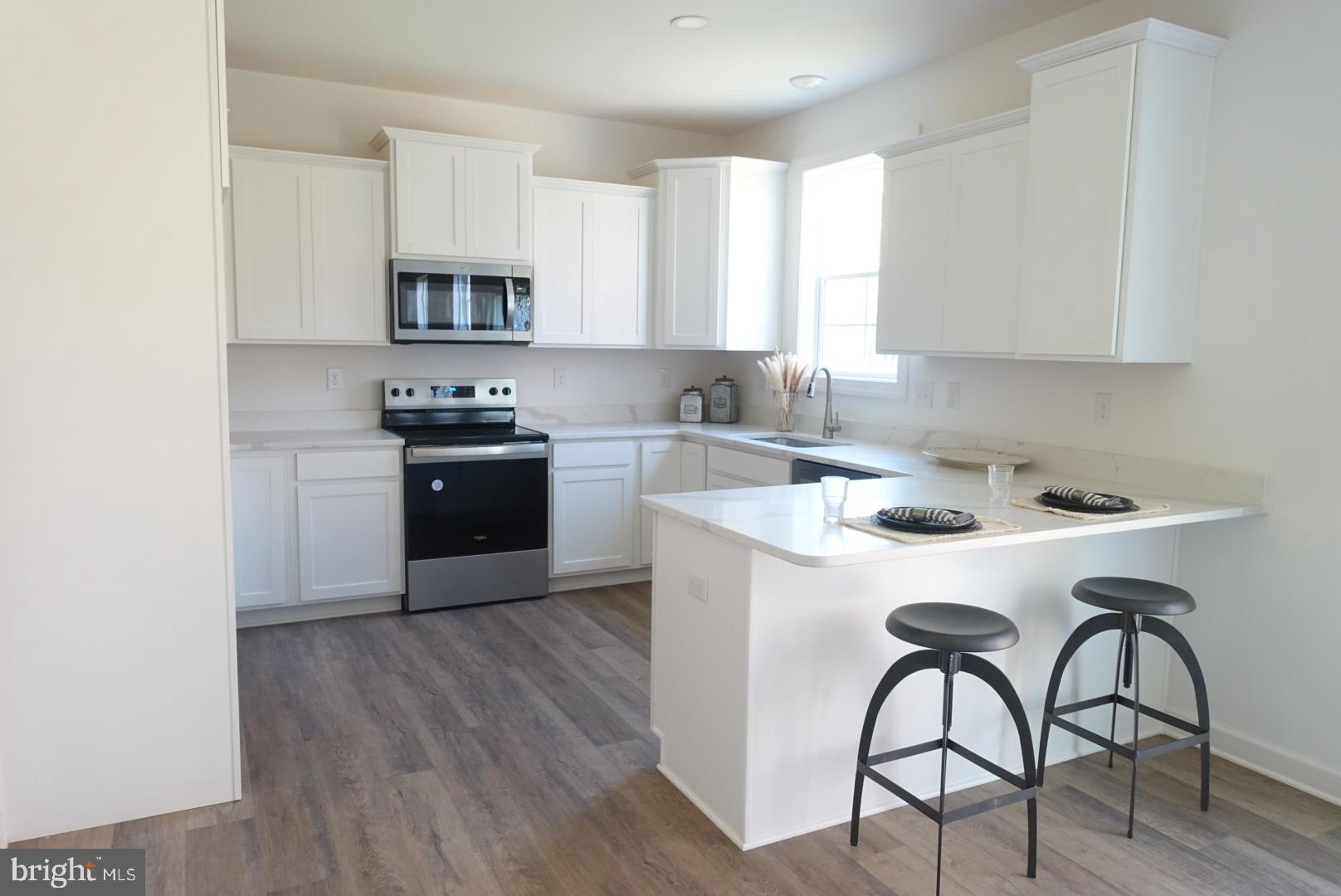 221 Kinneman Road, Unit 28 Abbottstown, PA 17301 - Photo 3 of 26 a kitchen with stainless steel appliances a sink a stove a table and chairs