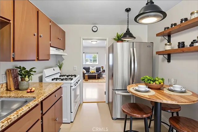 a kitchen with stainless steel appliances a dining table chairs stove and refrigerator