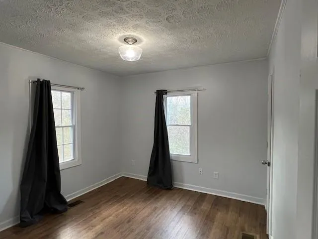 an empty room with wooden floor and window