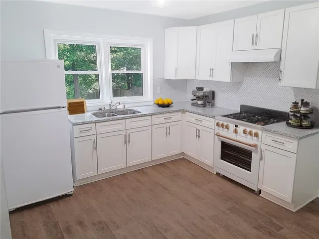 a kitchen with a sink white cabinets and white appliances
