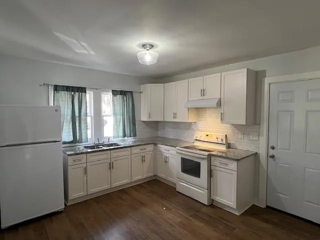 a kitchen with stainless steel appliances granite countertop white cabinets a sink a stove a refrigerator and white cabinets