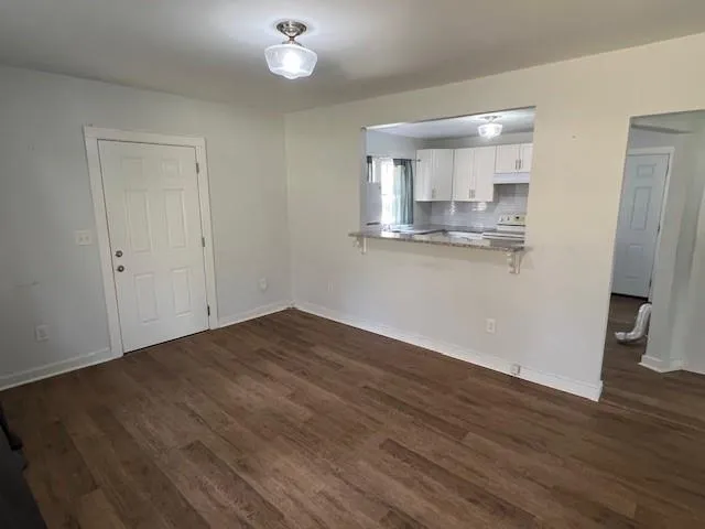 a view of kitchen and empty room with wooden floor