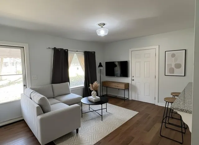a living room with furniture a flat screen tv and a window