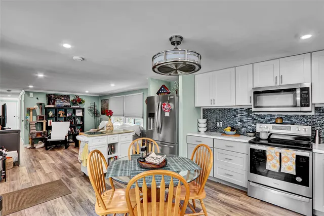 a kitchen with stainless steel appliances a dining table chairs stove refrigerator and cabinets