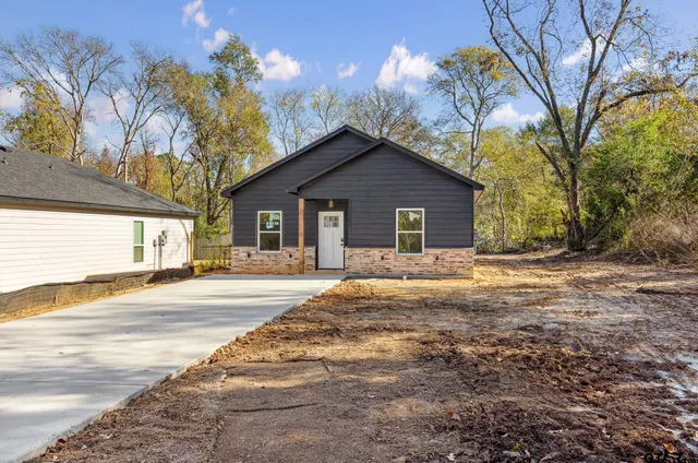 a view of a house with a yard and large trees